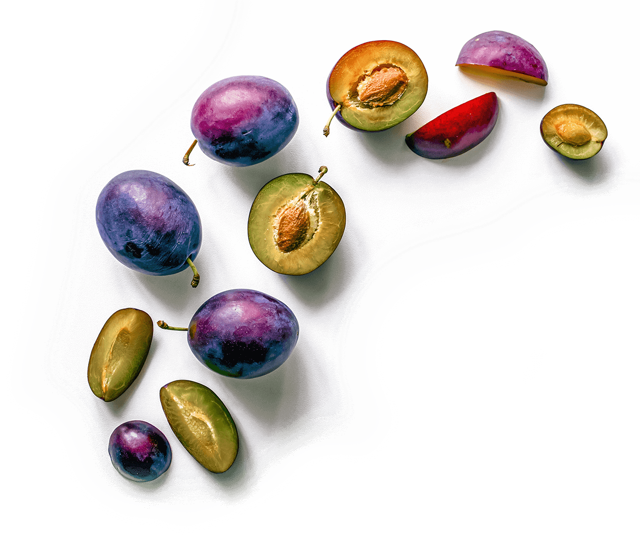 Eine Vielzahl von ganzen und halbierten Pflaumen in Violett- und Grüntönen, kunstvoll arrangiert auf einem weißen Hintergrund.