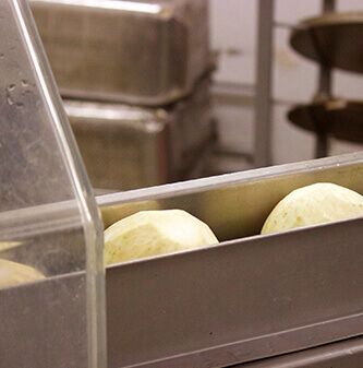 Nahaufnahme von geschälten, runden Kartoffeln auf einem Förderband in einer Lebensmittelverarbeitungsanlage.